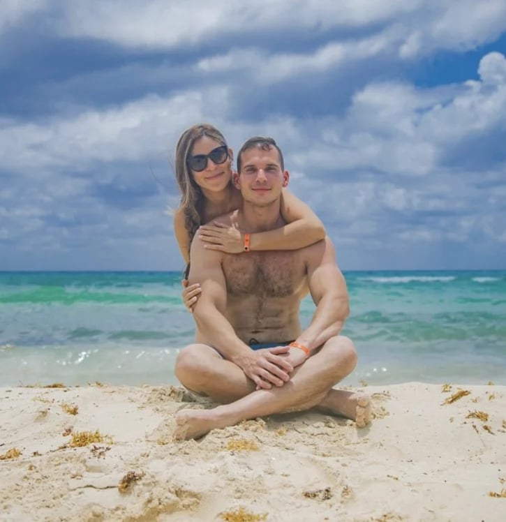 Pareja sonriendo en la playa con agua turquesa
