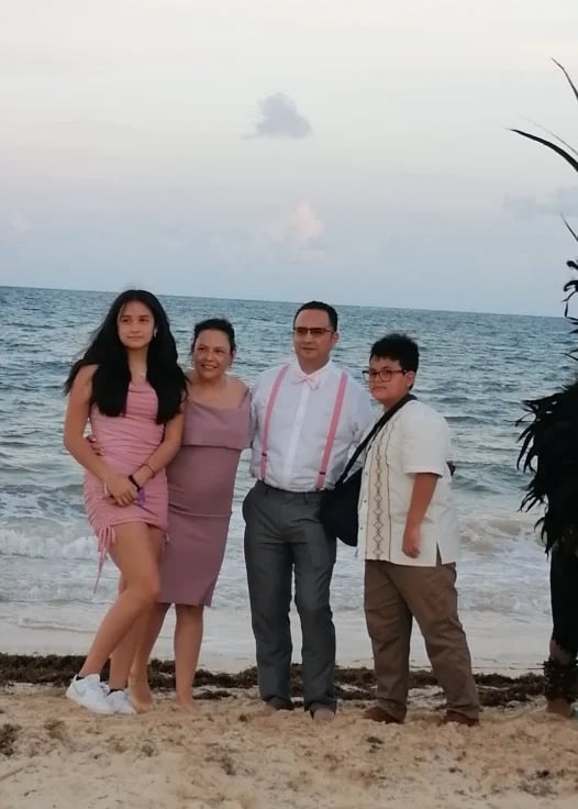 Cuatro personas juntas en la playa con el océano y cielo de fondo